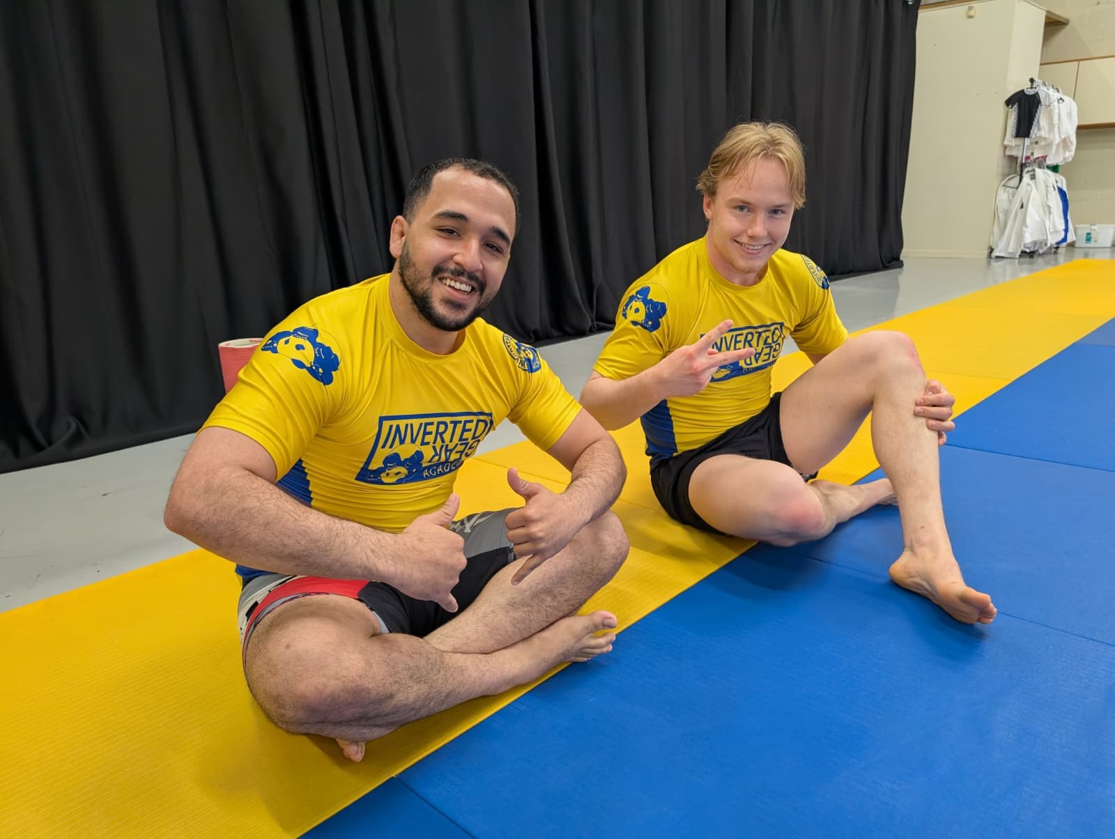 Two students in yellow Inverted Gear Academy rashguards on the mats