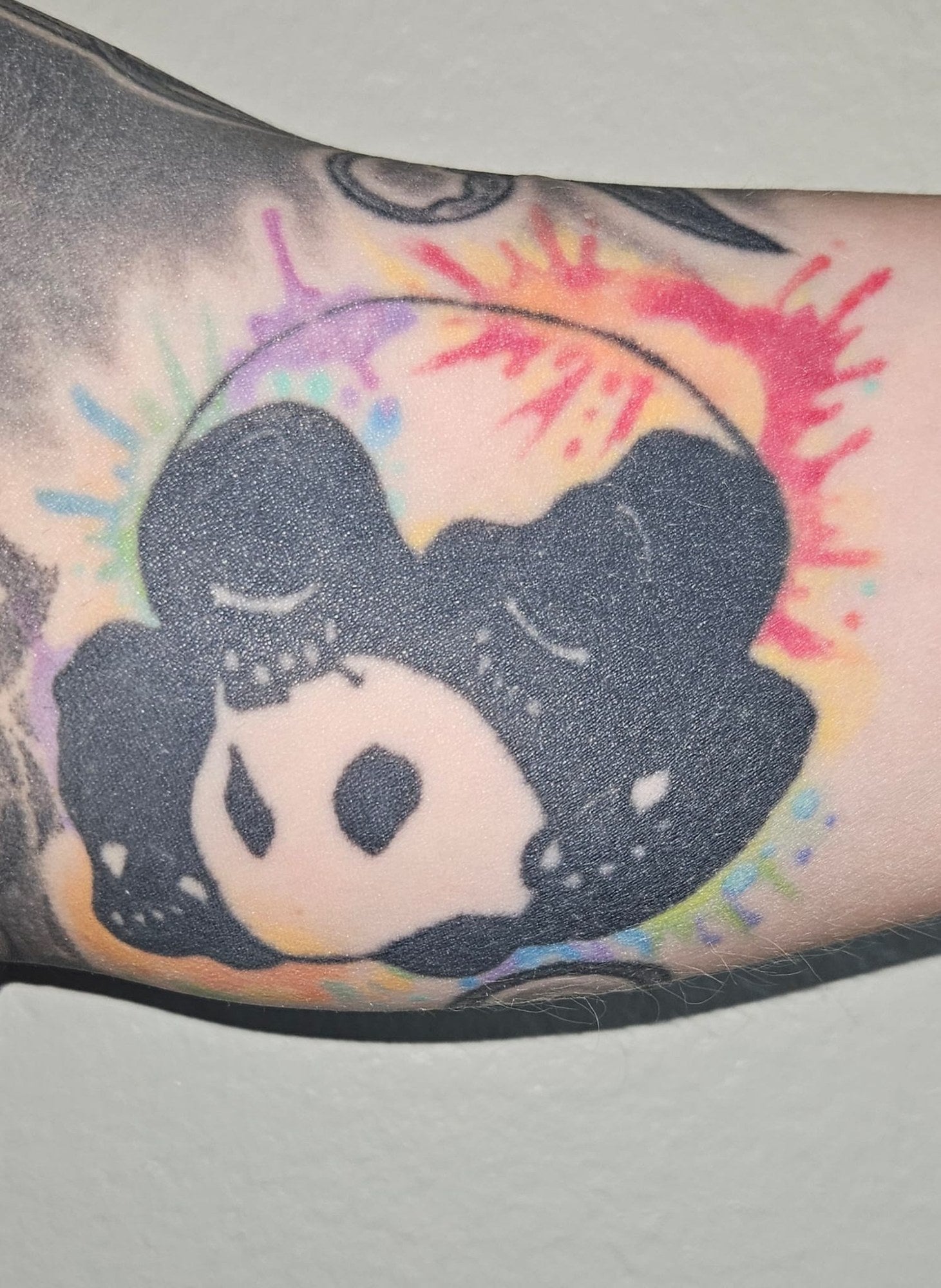 The Inverted Gear panda tattooed on a customer's arm over a watercolour splash